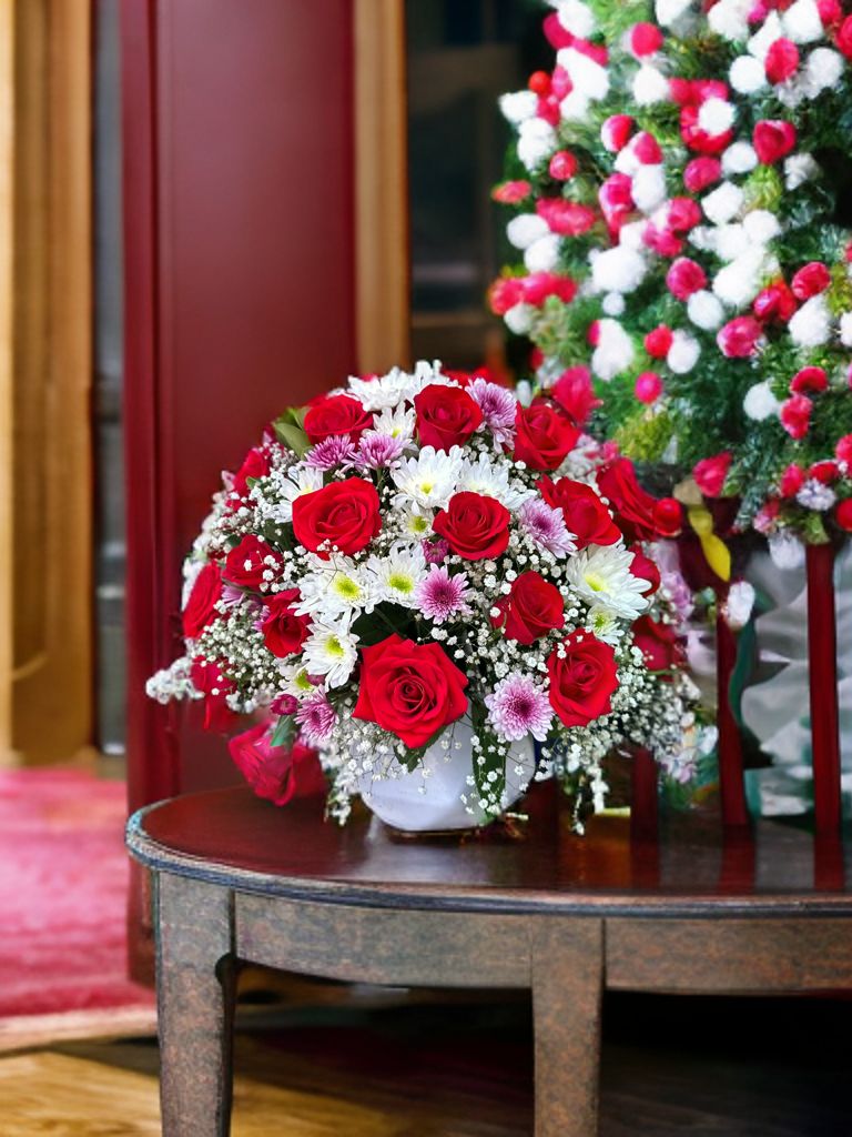 Arreglo grande con 24 rosas, gerberas de diferentes tonos, solidago y follaje verde en una base de cerámica