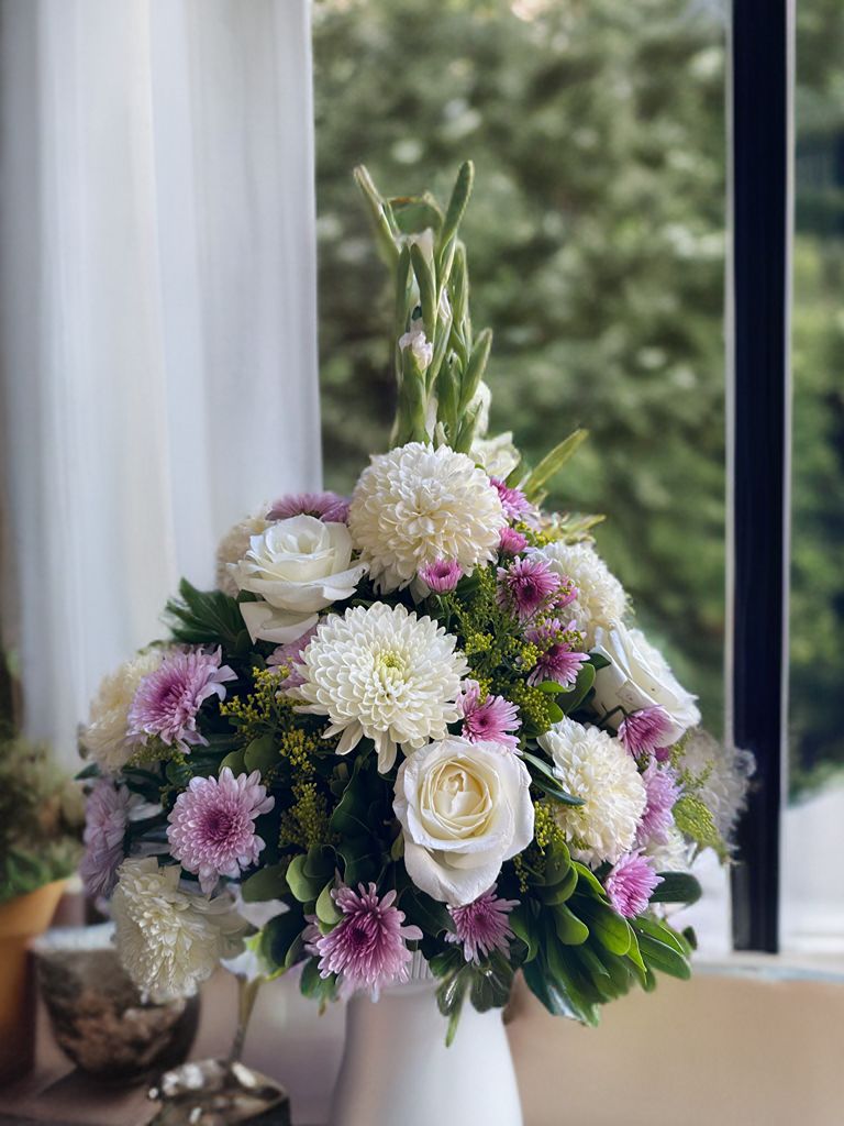 Arreglo mediano con rosas blancas, crisantemo en blanco y morado, complementado con solidago y un toque de follaje.